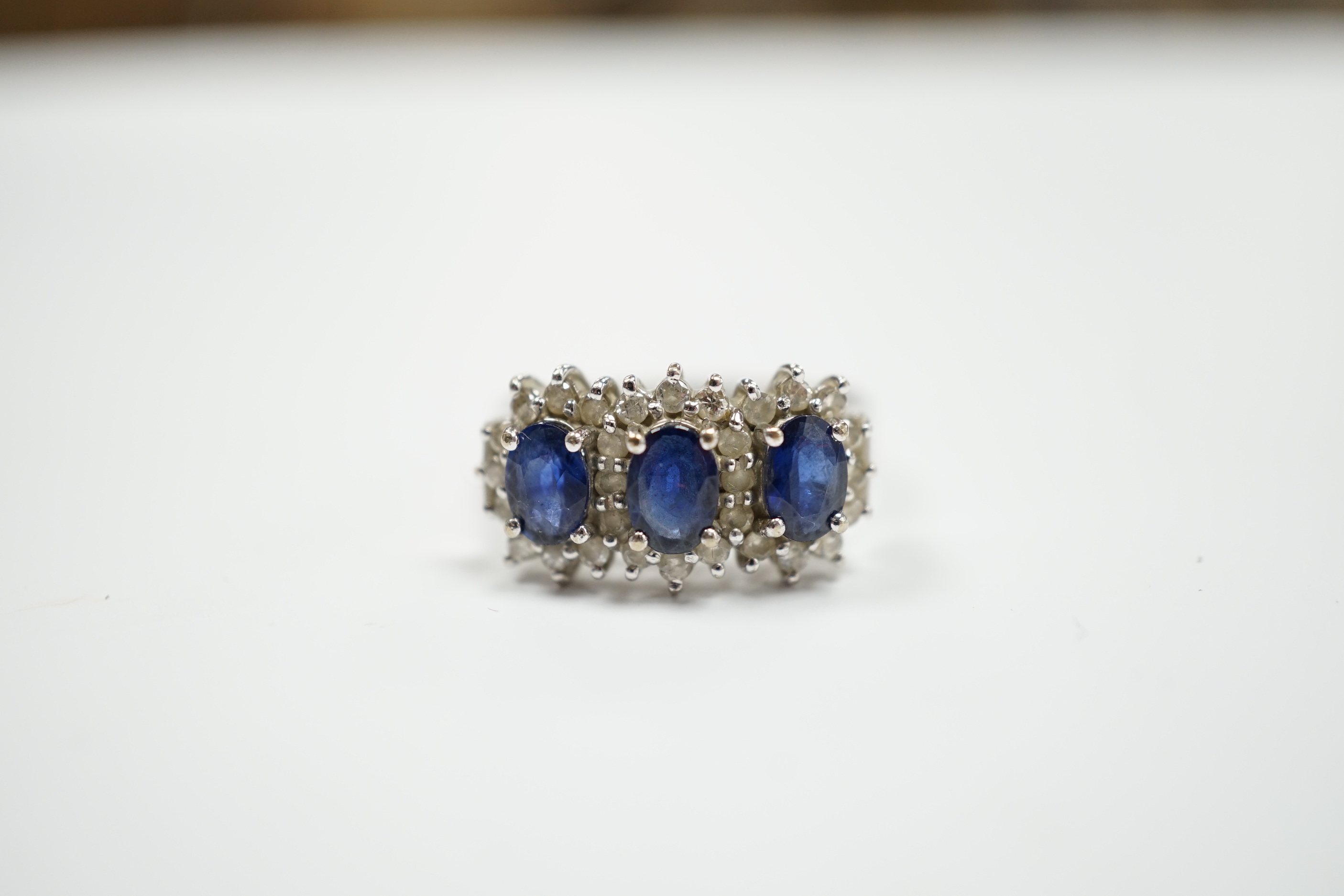 An 18k white metal, sapphire and diamond set triple cluster ring, size Q. gross weight 5.8 grams.